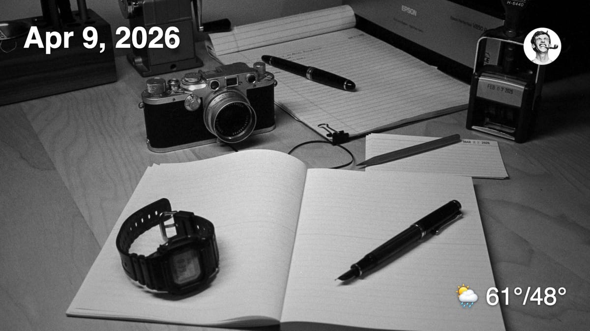 Black and white film photo of analog tools on desk (watch, fountain pen, film camera, etc)